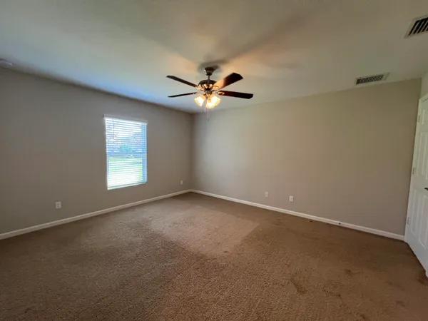 an empty room with windows and fan