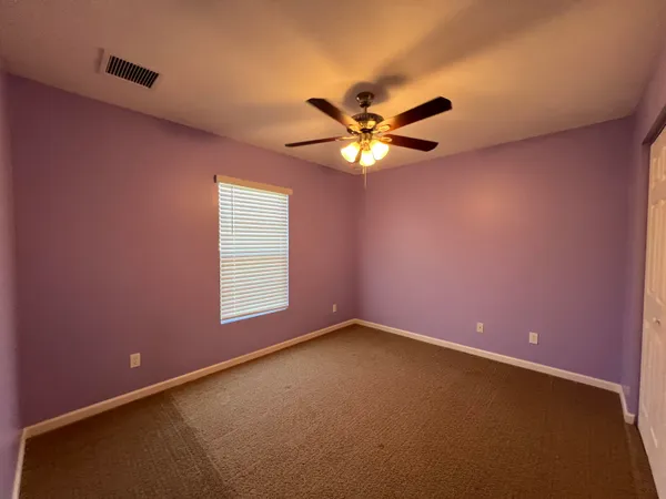 an empty room with a window and a ceiling fan