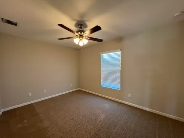 an empty room with a window and a fan
