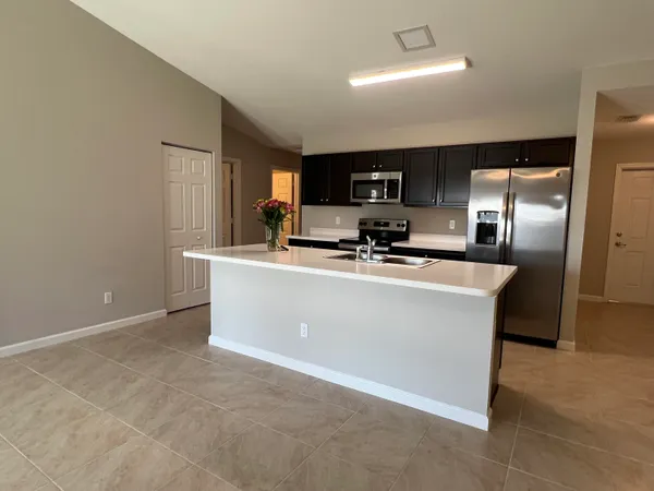 a room with kitchen island stainless steel appliances a sink a refrigerator a microwave a sink and cabinets