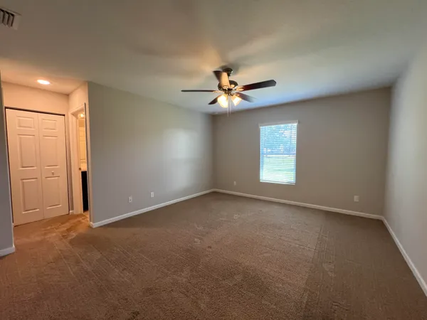 an empty room with windows and ceiling fan