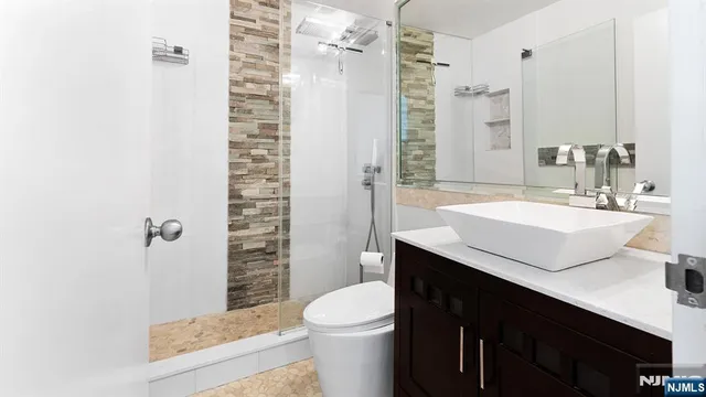 a bathroom with a sink a toilet a mirror and shower