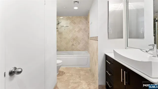a bathroom with a granite countertop sink a toilet and shower