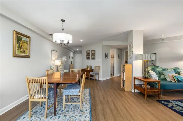 a dining room with wooden floor a chandelier a wooden table and chairs