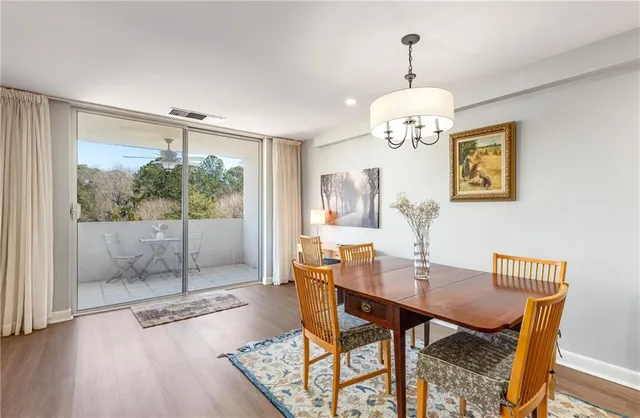 a dining room with wooden floor a chandelier a glass table and chairs