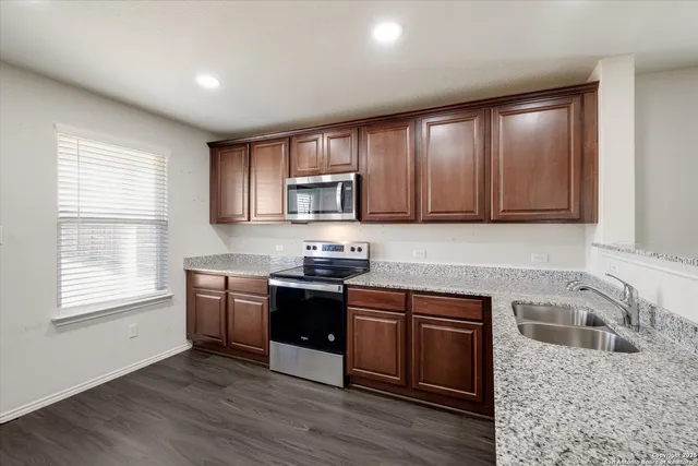 a kitchen with stainless steel appliances granite countertop wooden cabinets granite counter tops and a window