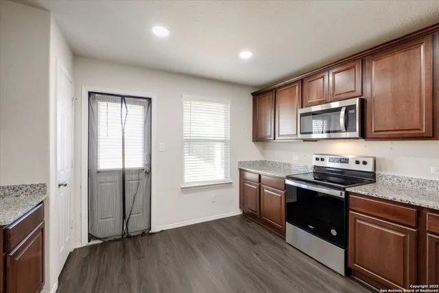 a kitchen with granite countertop wooden floors appliances and sink