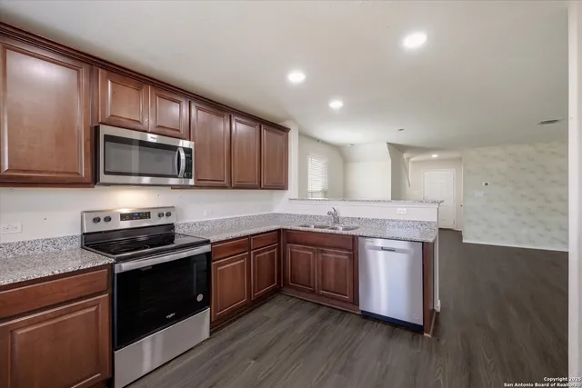a kitchen with stainless steel appliances granite countertop wooden cabinets stove top oven and sink