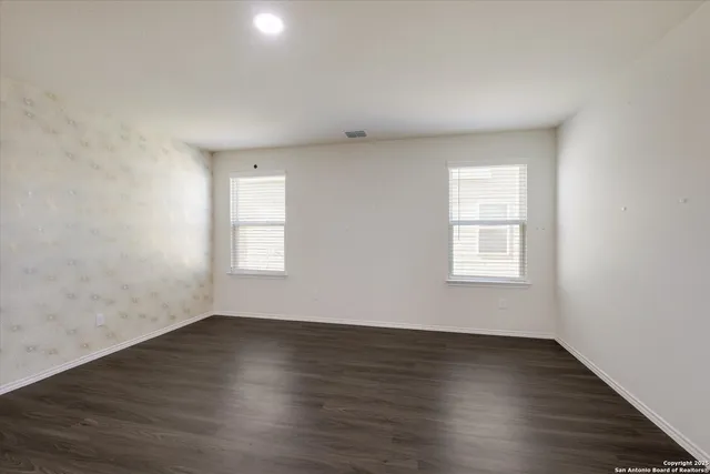 an empty room with wooden floor and windows
