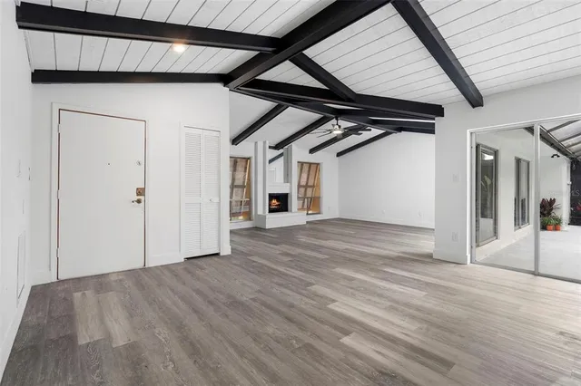 a view of an empty room with wooden floor and a ceiling fan