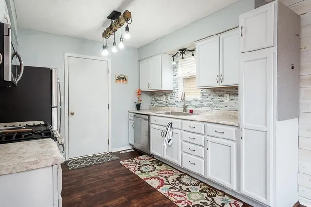 a kitchen with granite countertop a sink cabinets stainless steel appliances and a window