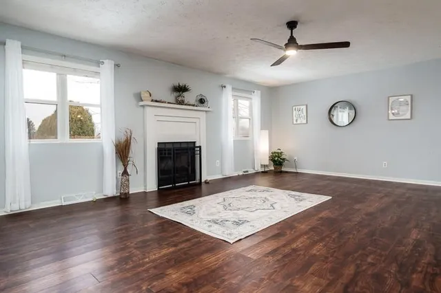 a view of an empty room with window and wooden floor