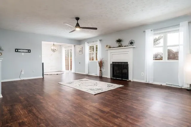 a view of an empty room with wooden floor fireplace and a window