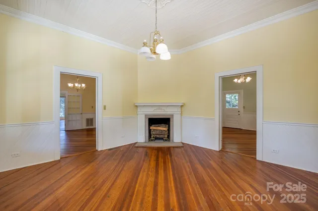 a view of an empty room with wooden floor fireplace and a window