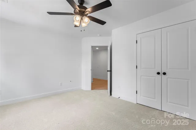 an empty room with closet and a chandelier fan