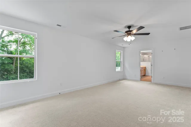 an empty room with windows and chandelier fan
