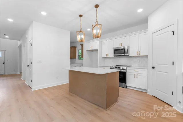 a large kitchen with stainless steel appliances kitchen island granite countertop a stove a sink a refrigerator and a wooden floor