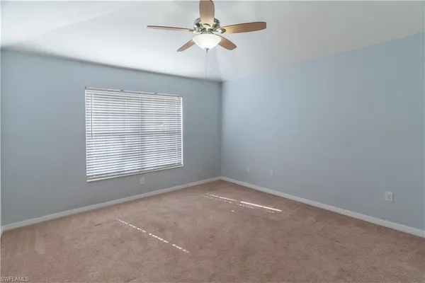 an empty room with a window and a fan