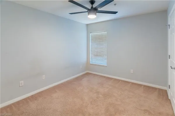an empty room with a window and a fan