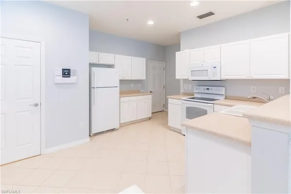 a kitchen with a sink a stove a refrigerator and white cabinets