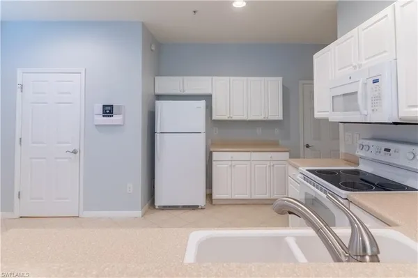 a kitchen with white cabinets and white appliances