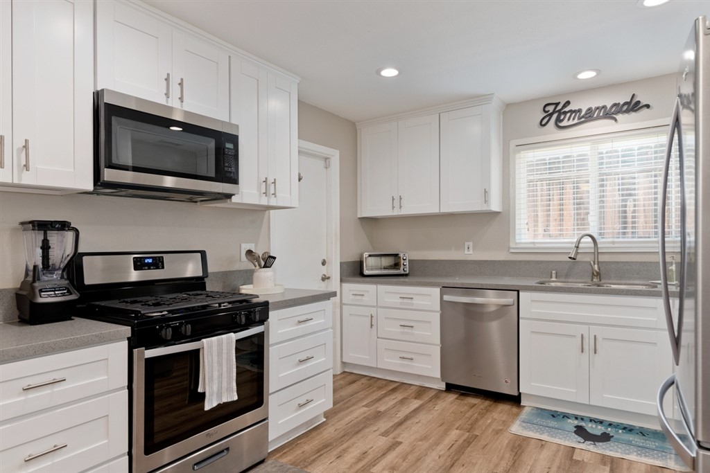9464 Lake Canyon Road Santee, CA 92071 - Photo 1 of 1 a kitchen with stainless steel appliances granite countertop white cabinets a sink a stove a microwave and wooden floors