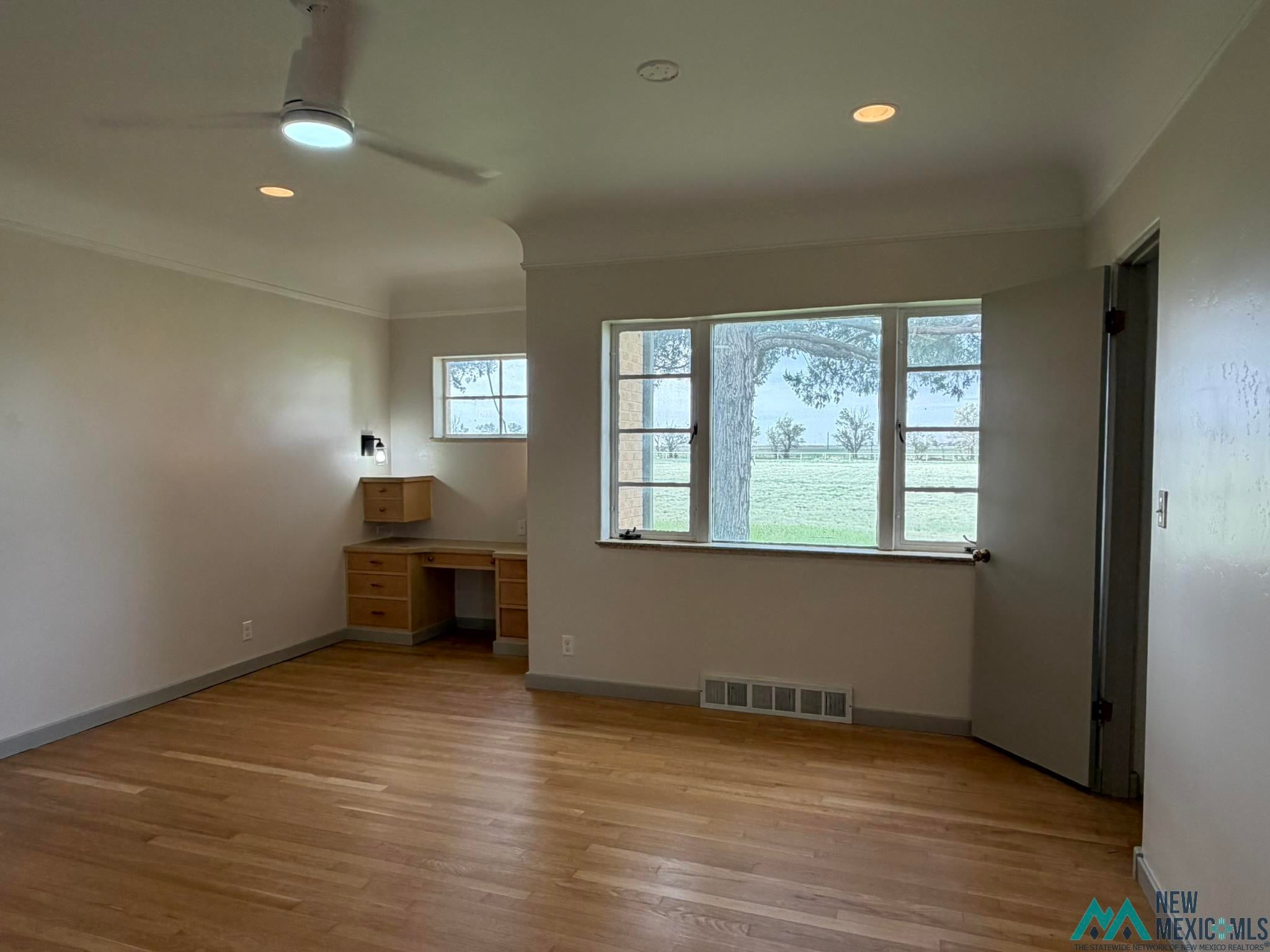 570 Curry Road North Clovis, NM 88101 - Photo 31 of 59 Spacious room featuring wood-finish flooring, a built-in wood desk with drawers, and a ceiling fan with integrated lighting
