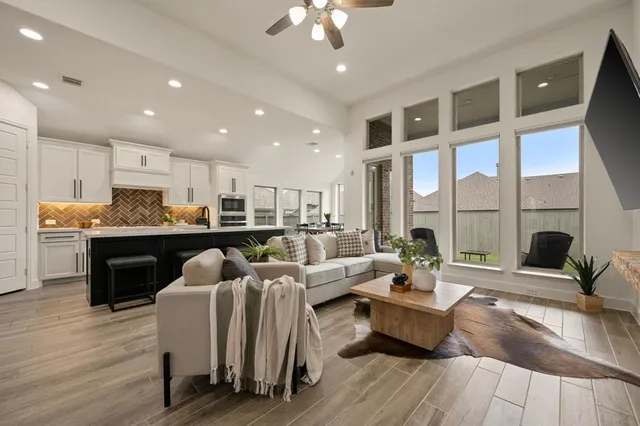 a living room with furniture kitchen and a large window
