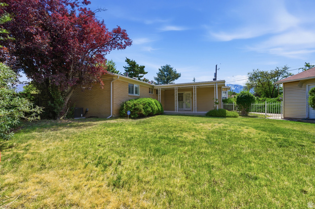 148 Tennyson Avenue Sandy, UT 84070 - Photo 41 of 55 Expansive backyard featuring a covered patio, mature landscaping, brick exterior, white framed windows, and a detached structure