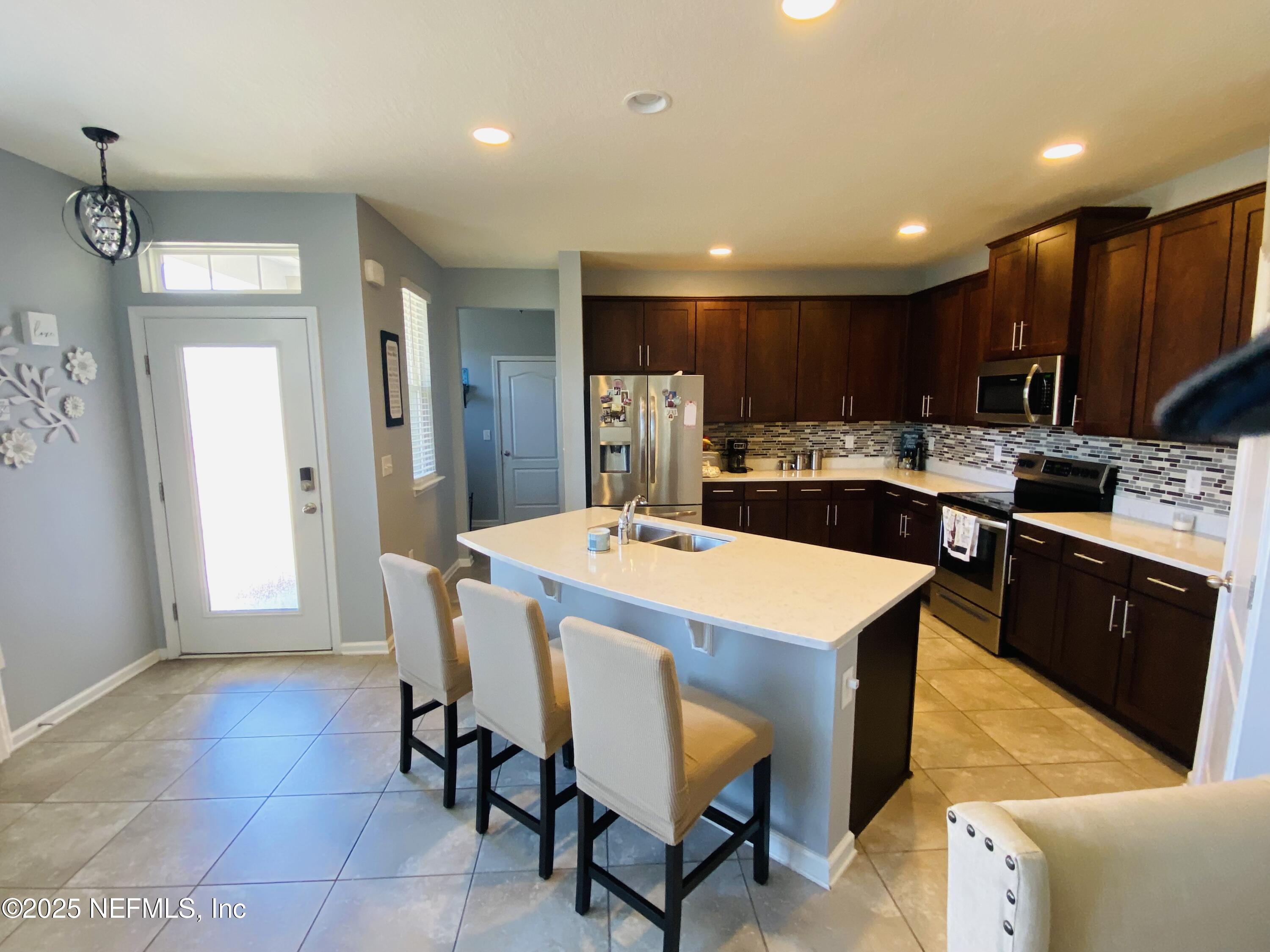 99 Bush Place St. Johns, FL 32259 - Photo 4 of 21 a kitchen with stainless steel appliances kitchen island granite countertop a table chairs sink and cabinets