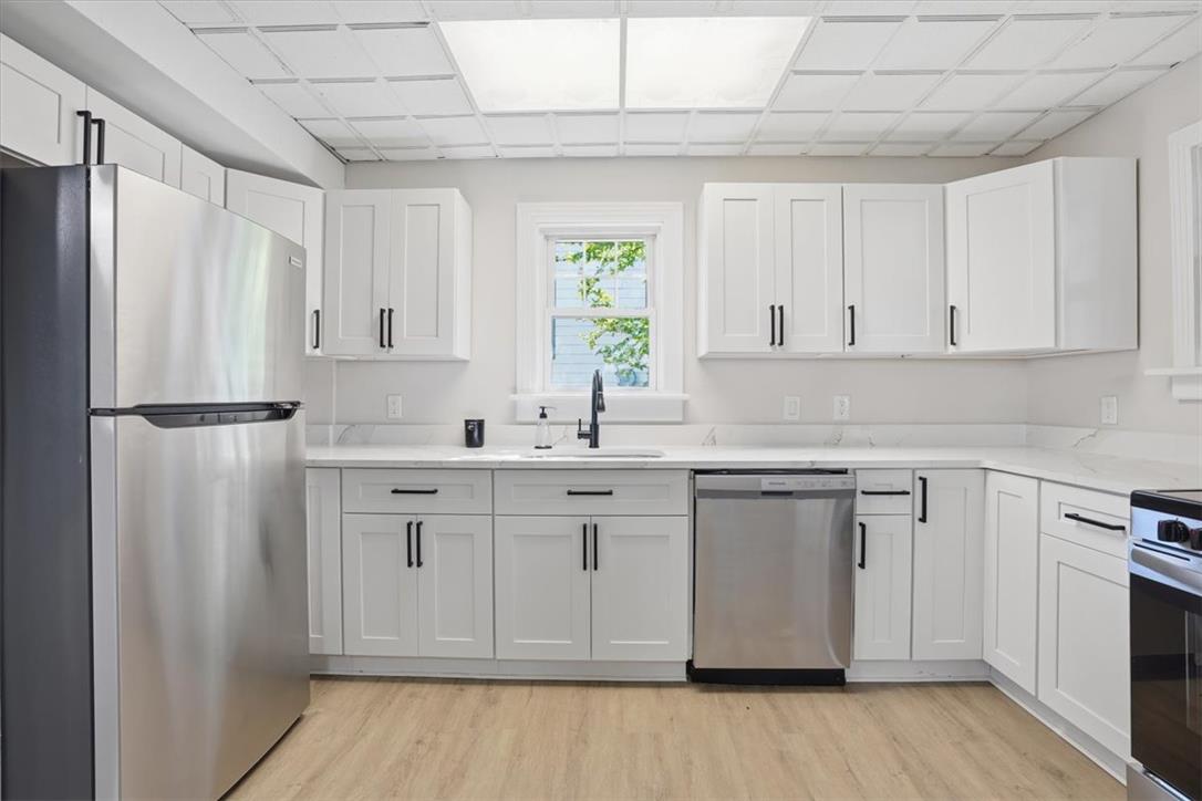 110 Messinger Street Bangor, PA 18013 - Photo 7 of 39 A contemporary kitchen features bright white cabinetry and sleek stainless steel appliances, creating a fresh aesthetic.