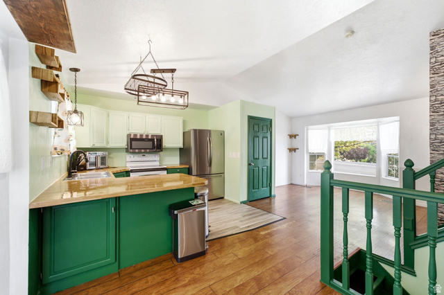2475 Church Street Layton, UT 84040 - Photo 8 of 27 Vaulted ceiling open-concept kitchen featuring light-toned upper cabinetry, green lower cabinetry, and wood-finish countertops