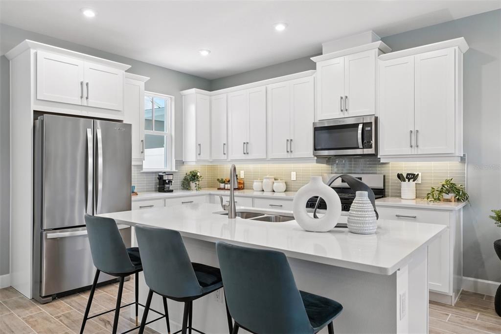 1792 Headland Loop Celebration, FL 34747 - Photo 6 of 31 a kitchen with stainless steel appliances a sink a stove a refrigerator cabinets and chairs