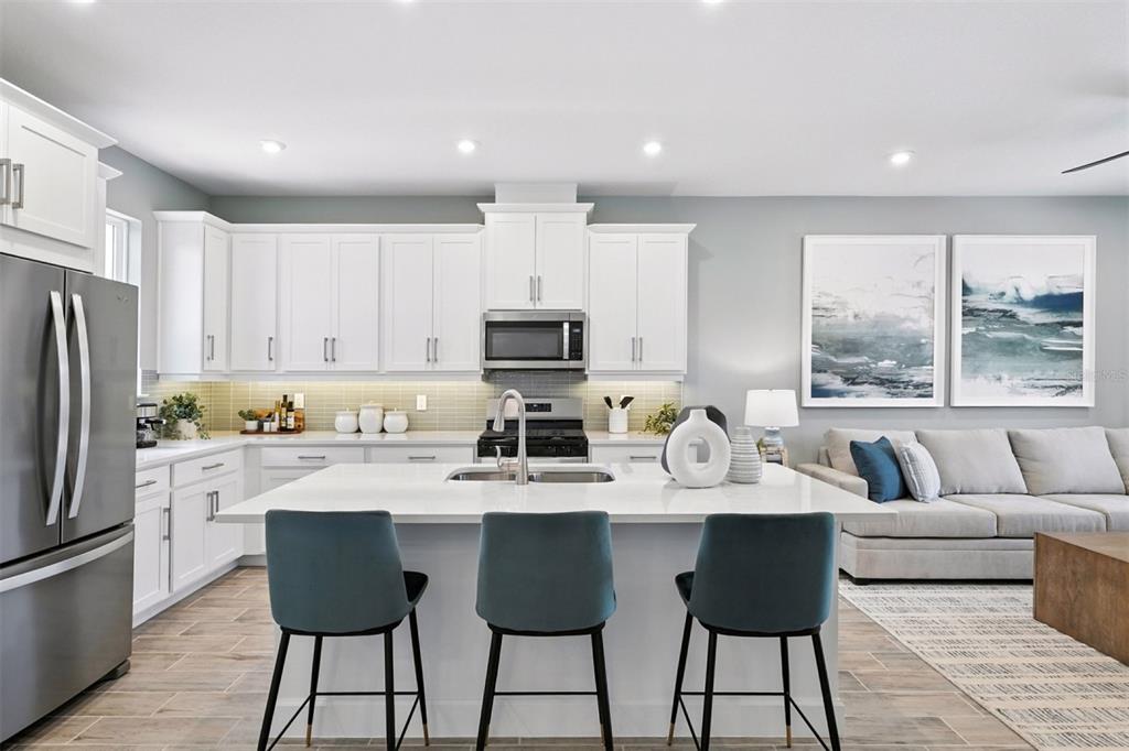 1792 Headland Loop Celebration, FL 34747 - Photo 7 of 31 a kitchen with stainless steel appliances granite countertop a refrigerator a sink dishwasher a stove and white cabinets with wooden floor