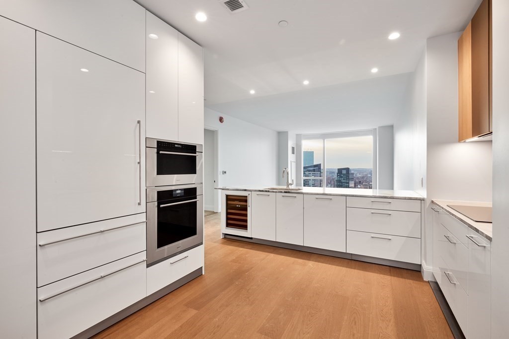 240 Devonshire Street, Unit U5404 Boston, MA 02110 - Photo 7 of 40 a large white kitchen with stainless steel appliances a large window and a refrigerator