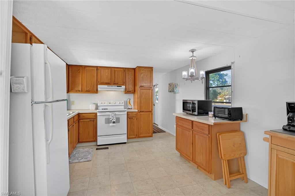 101 Rookery Road Naples, FL 34114 - Photo 12 of 43 a kitchen with stainless steel appliances granite countertop a stove top oven a refrigerator a sink dishwasher with a dining table and chairs