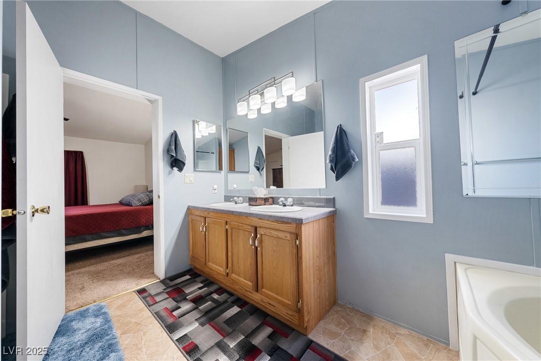 633 East Simkins Road Pahrump, NV 89060 - Photo 13 of 25 Primary bathroom with a garden tub, double vanity, a sink, and connected bathroom