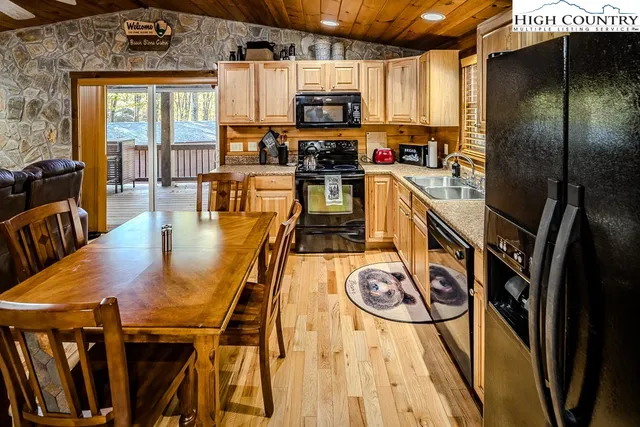 a kitchen with stainless steel appliances granite countertop a stove top oven a sink a dining table and chairs with wooden floor