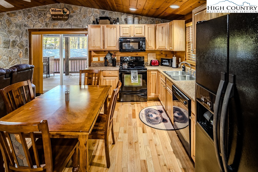 719 Pine Ridge Road Beech Mountain, NC 28604 - Photo 5 of 32 a kitchen with stainless steel appliances granite countertop a stove top oven a sink a dining table and chairs with wooden floor