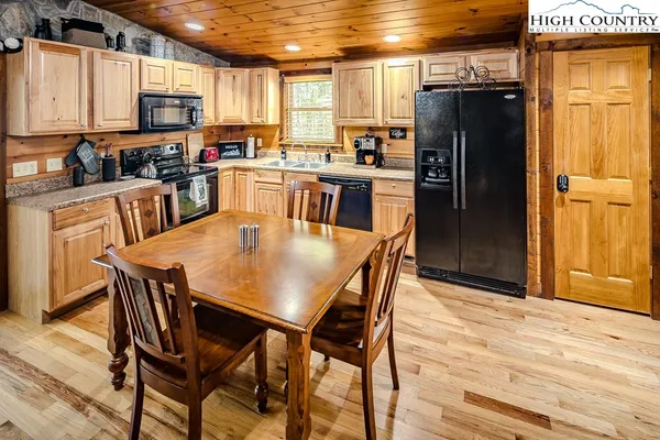 a kitchen with stainless steel appliances granite countertop a dining table chairs refrigerator and microwave