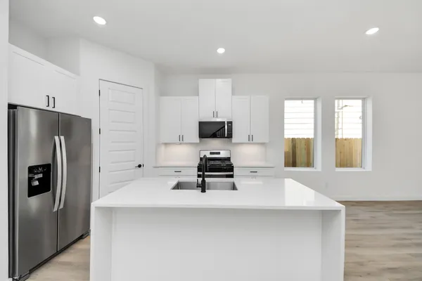 a kitchen with a refrigerator a stove and a sink with wooden floor