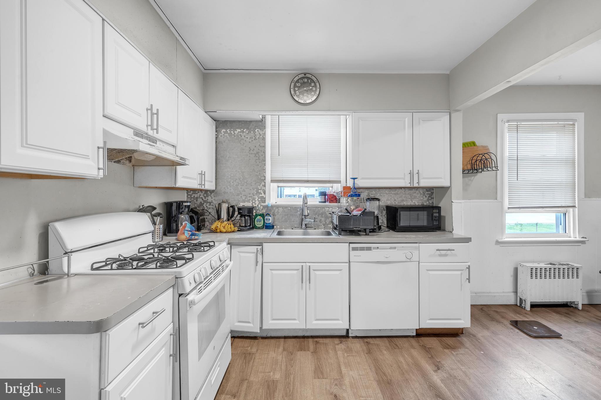 438 Holly Road Lansdowne, PA 19050 - Photo 6 of 17 a kitchen with stainless steel appliances granite countertop a sink stove and white cabinets with wooden floor