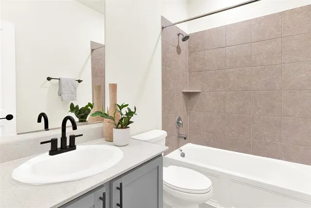 a bathroom with a granite countertop sink a toilet a mirror and shower