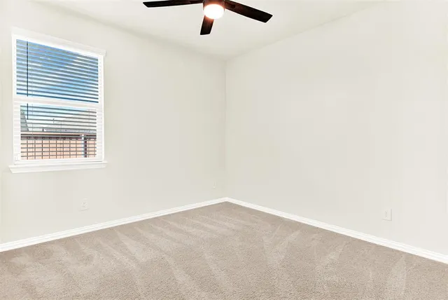 an empty room with a window and a ceiling fan