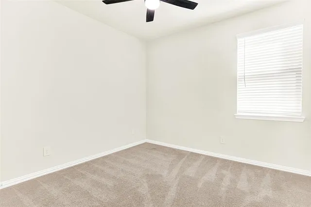 an empty room with a window and a ceiling fan