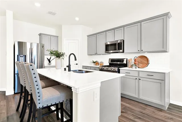 a kitchen with stainless steel appliances a stove a sink a microwave and cabinets