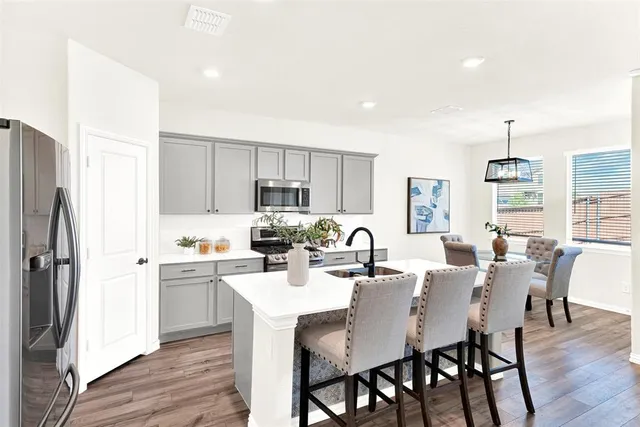 a kitchen with a dining table chairs refrigerator and cabinets
