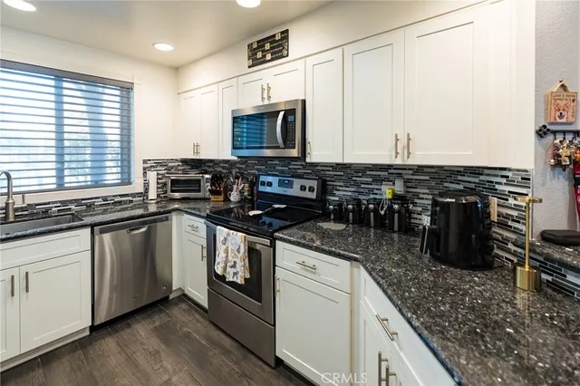 a kitchen with stainless steel appliances granite countertop a stove a sink and a microwave