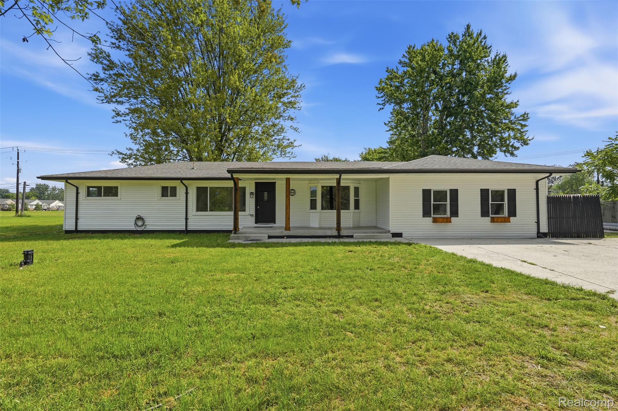 4655 Denton Road Canton, MI 48188 - Photo 1 of 54 White siding exterior, dark roof, prominent window shutters, front porch with wood-finish columns, and a concrete driveway