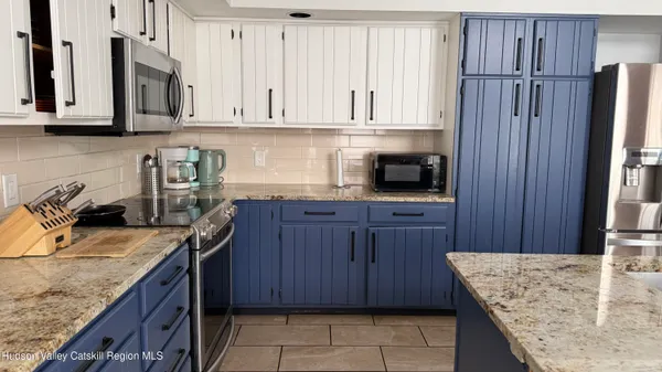 a kitchen with stainless steel appliances granite countertop a sink dishwasher stove and refrigerator with wooden cabinets